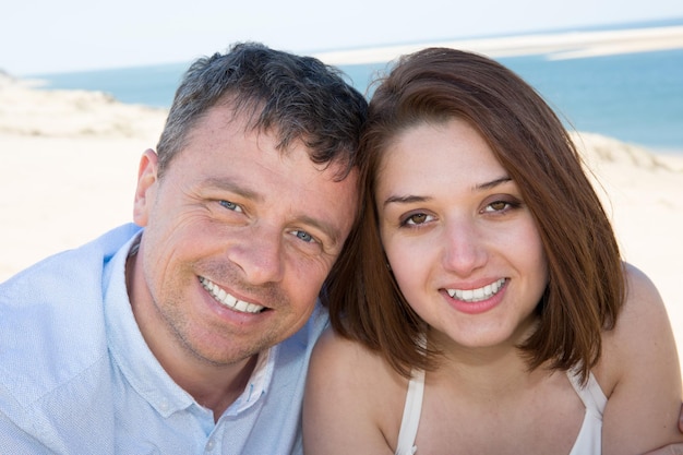 Feliz casal romântico na praia olhando para a câmera