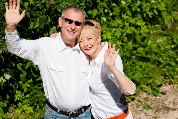 Feliz casal sênior ao ar livre, agitando as mãos