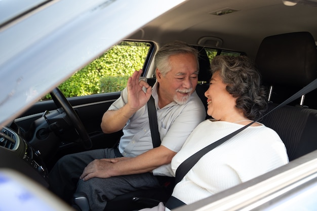 Feliz casal sênior asiático sentado no carro e dirigindo o carro na viagem de viagem.