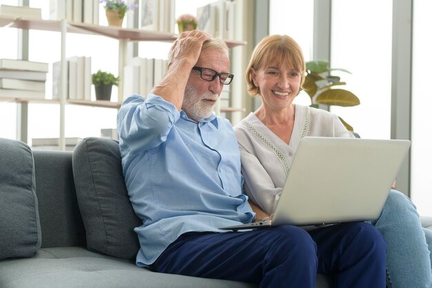 Feliz casal sênior caucasiano usando laptop em casa