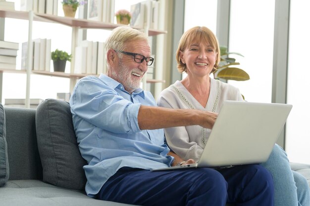 Feliz casal sênior caucasiano usando laptop em casa