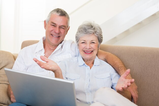 Feliz casal sênior com laptop no sofá