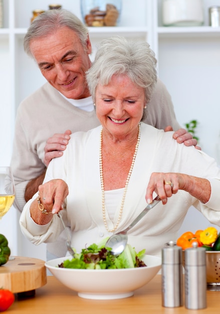 Feliz casal sênior comendo uma salada na cozinha