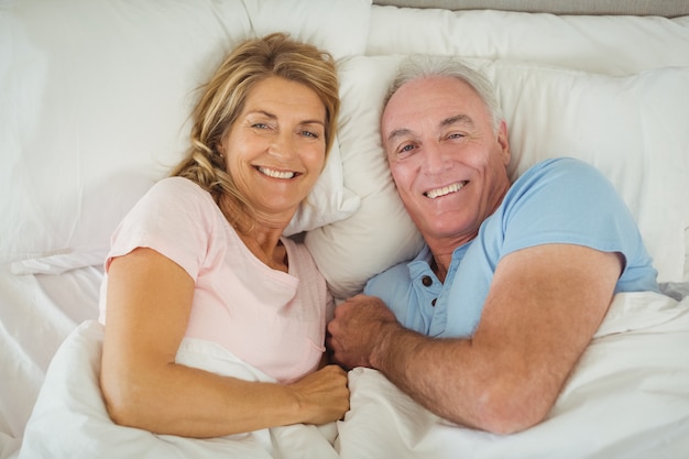 Feliz casal sênior deitada na cama