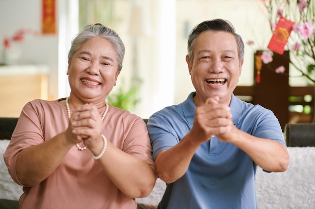 Feliz casal sênior fazendo gesto de saudação e olhando para a câmera