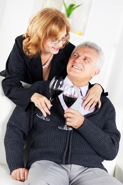 Feliz casal sênior no interior de casa desfrutando de um copo de vinho.