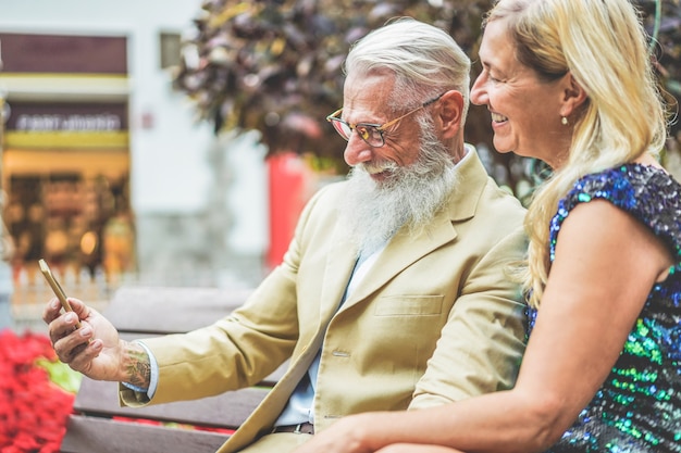 Feliz casal sênior se divertindo usando o aplicativo de smartphone - pessoas maduras usando as novas tendências da tecnologia