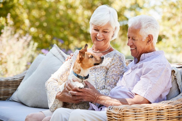 Foto feliz casal sênior sentado com um cachorro de estimação no jardim