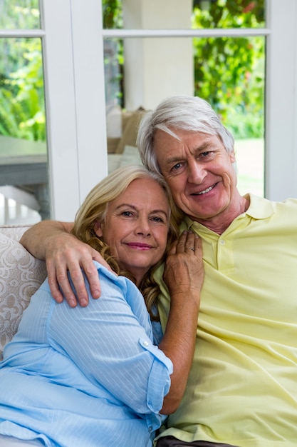 Feliz casal sênior sentado no sofá em casa