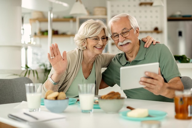 Feliz casal sênior usando o touchpad enquanto faz videochamada em casa