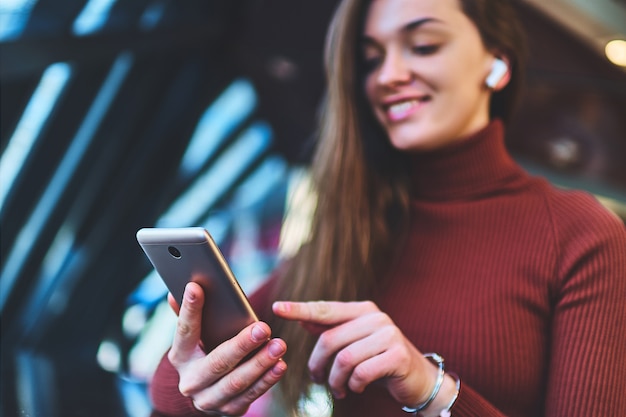 Feliz caucasiana morena jovem feliz casual com fones de ouvido sem fio e telefone celular.