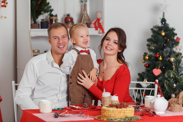 Feliz celebración familiar del año nuevo la madre, el padre y el pequeño hijo sentados en la mesa