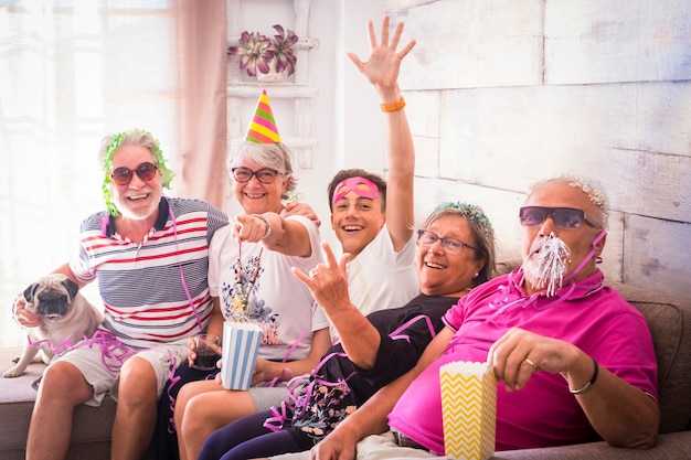 Foto feliz celebración de la víspera de año nuevo en casa con la familia de personas jóvenes y mayores que se divierten todos juntos y mirando a la cámara: las personas alegres de generaciones mixtas disfrutan de la fiesta en el interior