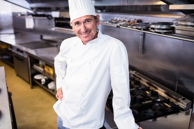 Foto feliz chef masculino em pé na cozinha comercial