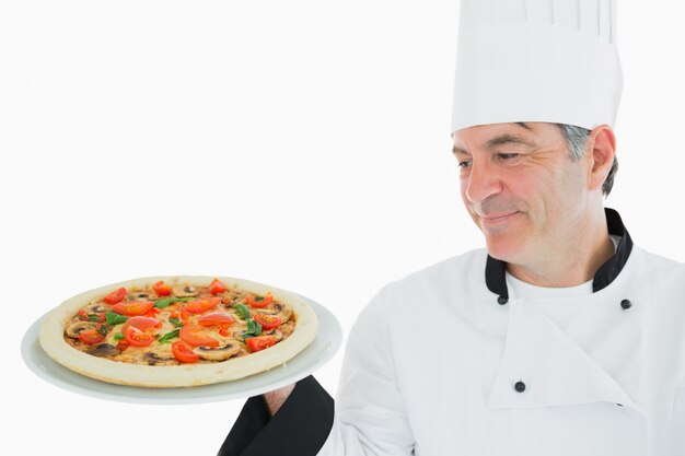 Feliz chef mirando pizza