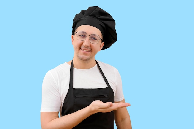 Feliz chef sonriente con gorra mirando a la cámara aislada de fondo azul