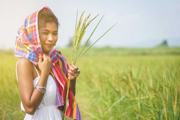 Feliz chica asiática disfrutar en campo de arroz verde, campo de Tailandia al atardecer