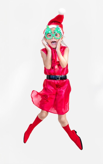Foto feliz chica asiática niño saltar y saludar con vestido rojo de papá noel en navidad y año nuevo concepto estacional para la publicidad