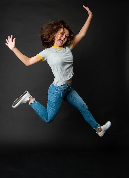 Foto feliz chica enérgica extática fresca saltando en el aire fondo oscuro, salta.