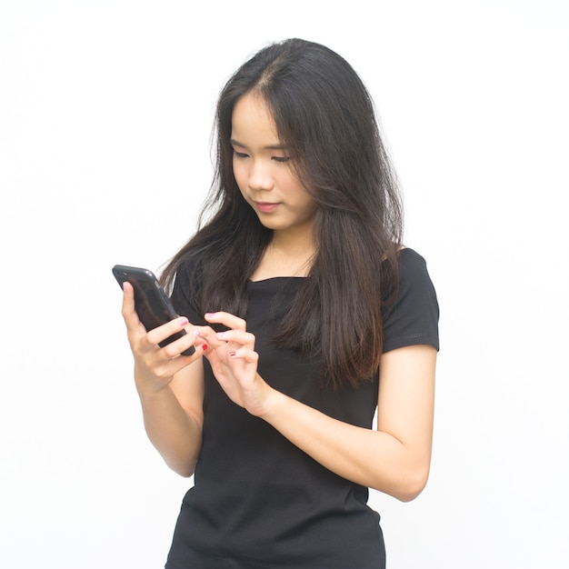 Feliz chica joven asiática sosteniendo y usando teléfono inteligente