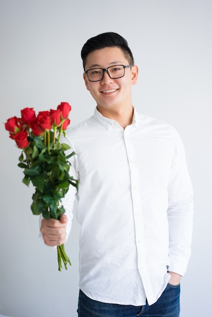Feliz chico asiático presentando racimo de rosas