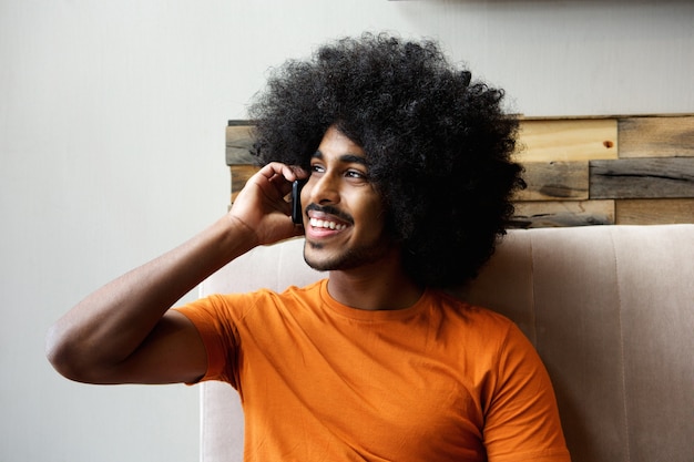 Feliz chico negro hablando por teléfono móvil en el interior