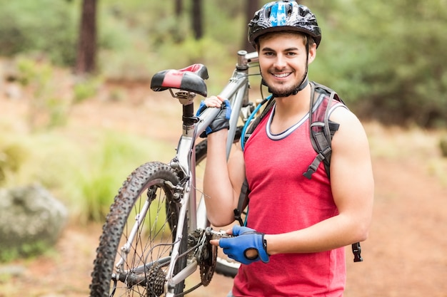 Feliz ciclista guapo con bicicleta y mirando a cámara