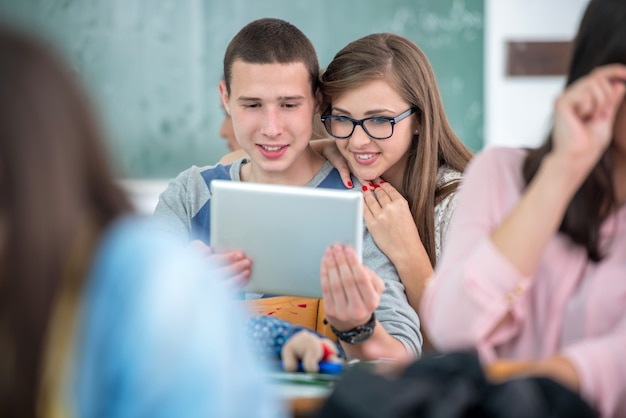 Feliz colegas de classe olhando um tablet