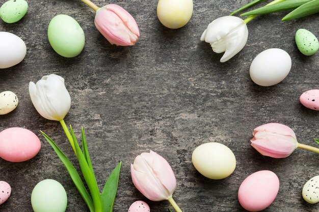 Feliz composición de Pascua Huevos de Pascua en mesa de colores con tulipanes amarillos Huevos de colores teñidos naturales Fondo vista superior con espacio de copia