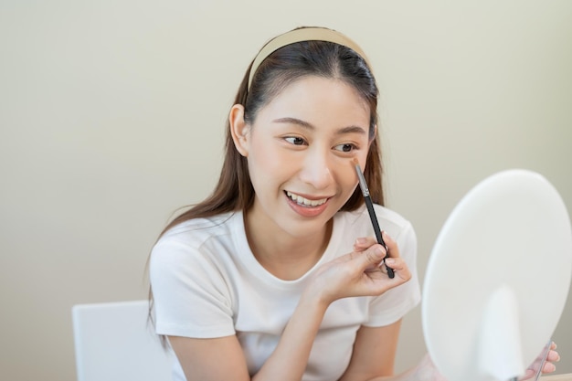 Feliz conceito de blogueiro de beleza bonito jovem asiático sorriso maquiagem rosto aplicando pincel blush em pó no olho olhando para o espelho As pessoas olham com espaço de cópia de estilo de moda natural