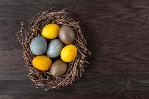 Feliz conceito de Páscoa Ovos de Páscoa coloridos em ninhos de pássaros na mesa de madeira Vista superior Copiar espaço