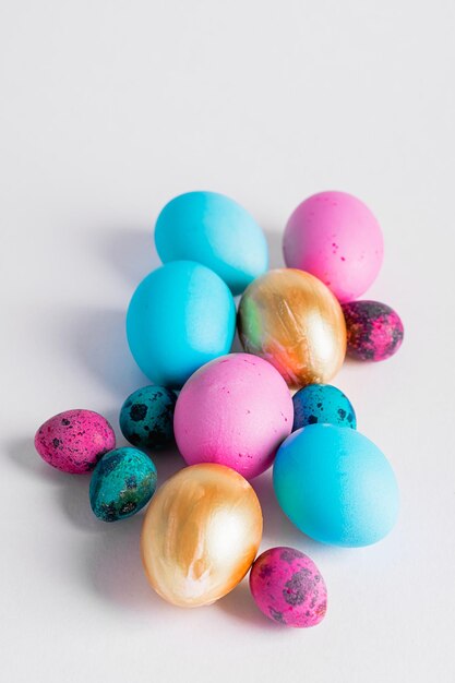 Feliz conceito de páscoa Ovos pequenos grandes de várias cores da moda estão em uma pilha em um fundo branco Copiar espaço