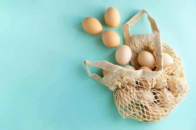 Foto feliz conceito de páscoa ovos rústicos naturais em um saco de barbante em um fundo azul o conceito mínimo um cartão de páscoa com uma cópia do local para o texto