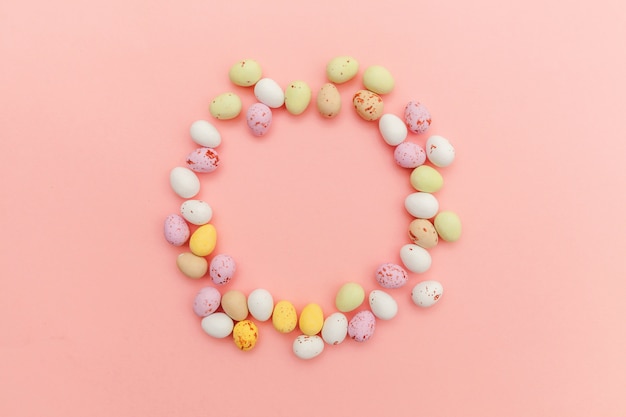Feliz concepto de Pascua. Huevos de chocolate de caramelo de Pascua y dulces de gelatina aislados sobre fondo rosa pastel de moda. Espacio de copia de vista superior plana simple minimalismo simple