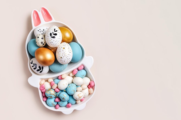 Feliz concepto de Pascua Lindo plato en forma de conejito con huevos de Pascua y dulces sobre fondo beige