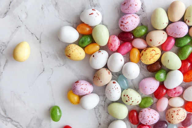 Feliz concepto de Pascua. Preparación para vacaciones. Dulces de Pascua huevos de chocolate y dulces de gelatina en mármol gris de moda. Minimalismo simple, plano, vista superior, espacio de copia.