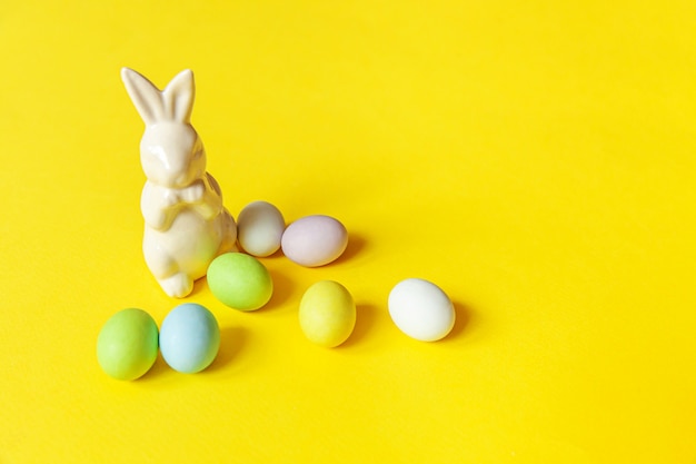 Feliz concepto de Pascua. Preparación para vacaciones. Pascua dulces huevos de chocolate dulces y conejito de juguete aislado en moda amarillo. Minimalismo simple copia espacio.