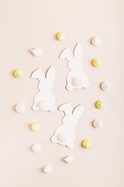 Feliz conejitos blancos de Pascua Huevos de Pascua y mini merengues en fondo rosa arriba y vista vertical