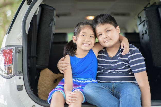 Feliz criança asiática sente-se no carro,