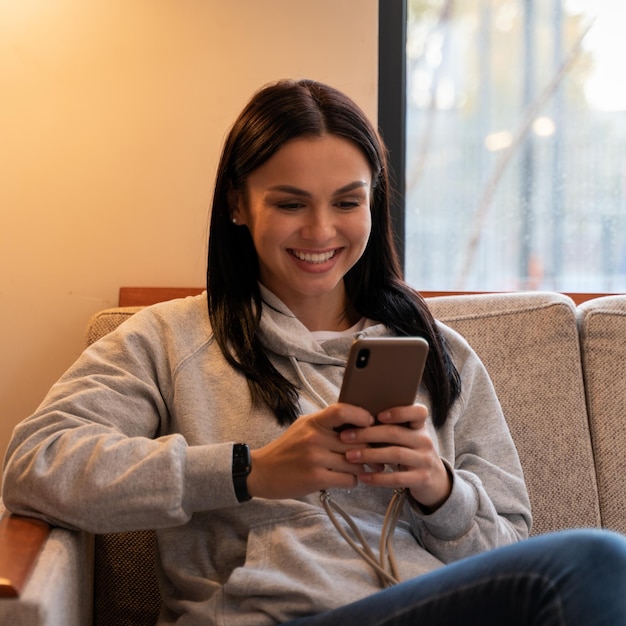 Feliz dama caucásica relajante en casa sola mientras comparte buenas noticias en las redes sociales a través del teléfono celular. Mujer sonriente disfruta de fin de semana pedir comida en línea en la aplicación de teléfono