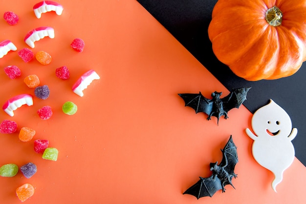 Feliz decoración de Halloween. Calabazas, caramelos gomosos, murciélagos y fantasmas sobre fondo naranja.