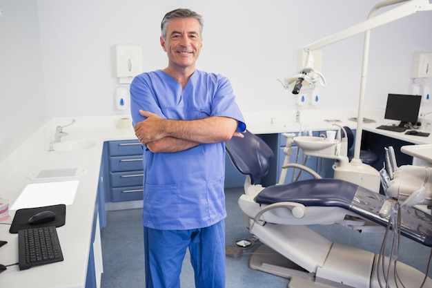 Feliz dentista de pé com os braços cruzados