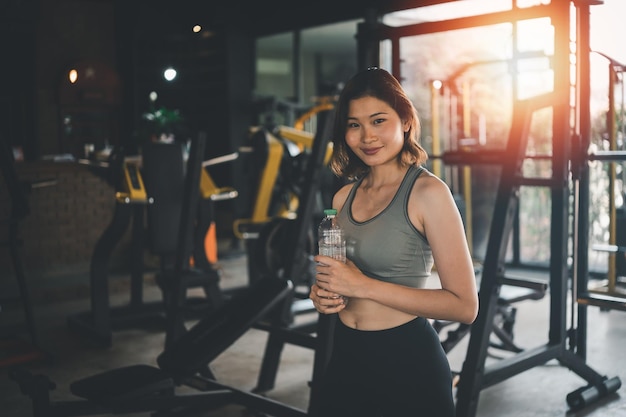 Feliz deporte mujeres ejercicio beber agua entrenamiento sonrisa entrenamiento en el gimnasio atleta niña entrenamiento fuerte y buena salud y fuerza