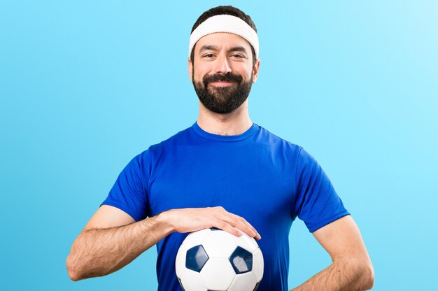 Feliz desportista engraçada segurando uma bola de futebol em fundo colorido