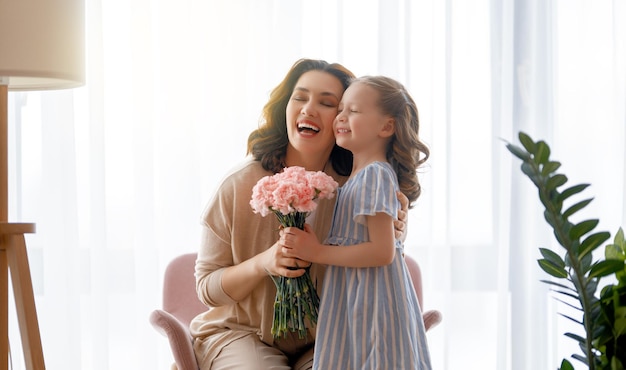 Feliz dia a filha da criança está parabenizando a mãe e dando-lhe flores