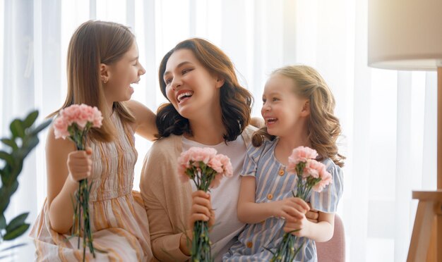 Feliz dia As filhas das crianças estão parabenizando a mãe e dando-lhe flores