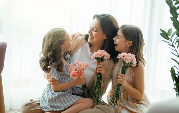 Feliz dia As filhas das crianças estão parabenizando a mãe e dando-lhe flores