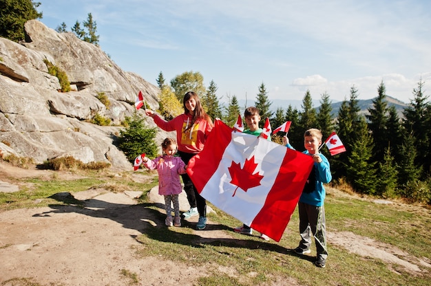 Feliz dia DE CANADA. Familia de madre con tres hijos celebra gran bandera canadiense en las montañas.