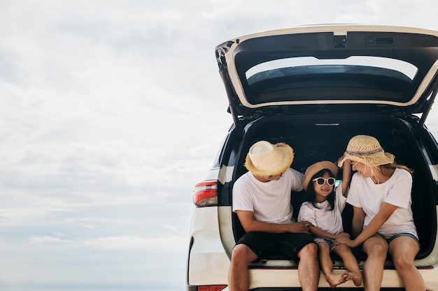 Feliz Dia da Família Pai mãe e filha desfrutando de viagem sentados no carro traseiro Pais e filhos viajando de férias na praia do mar família se divertindo nas férias de verão na praia com automóvel