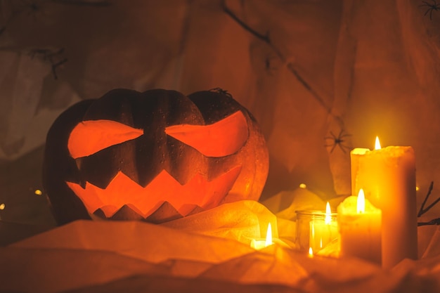 Feliz dia das bruxas jack o lanterna esculpida abóbora teia de aranha fantasma e luzes brilhantes no escuro dentro de casa decorações atmosféricas assustadoras de halloween com velas à noite gostosuras ou travessuras